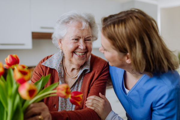 Senior woman and nurse with a tulip bouquet.