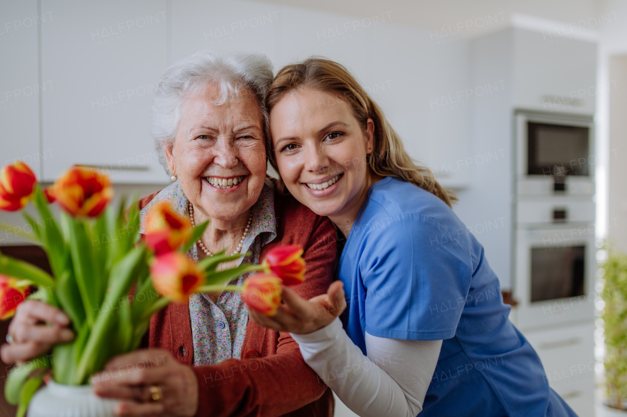 Senior woman and nurse with a tulip bouquet.