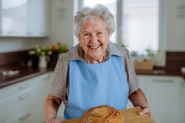 Portrait of senior woman with a fresh baked bread.