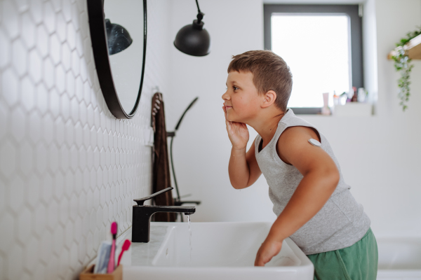 The diabetic boy getting ready in the morning, while wearing a continuous glucose monitoring sensor on his arm. CGM device making life of school boy easier, helping manage his illness and focus on other activities.