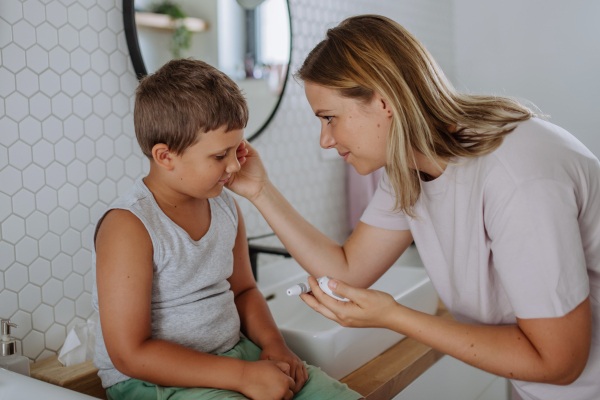 Mother checking her son's blood glucose level at home using a fingerstick glucose meter. The diabetic boy waiting for results from his blood test. Mother caressing her son's cheek.