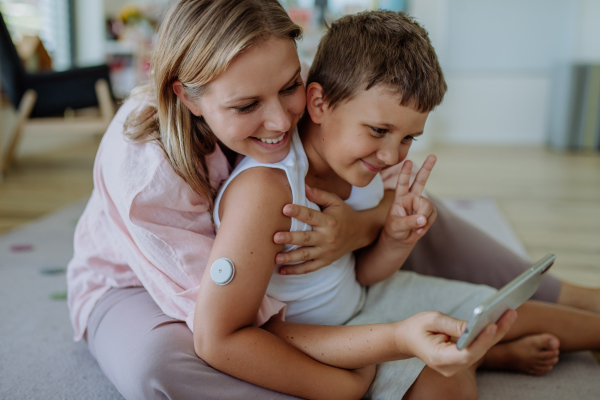 Diabetic boy using a continuous glucose monitor every day, living normal life, video calling his family. The CGM device makes the life of the schoolboy easier, helping manage his illness and focus on other activities.