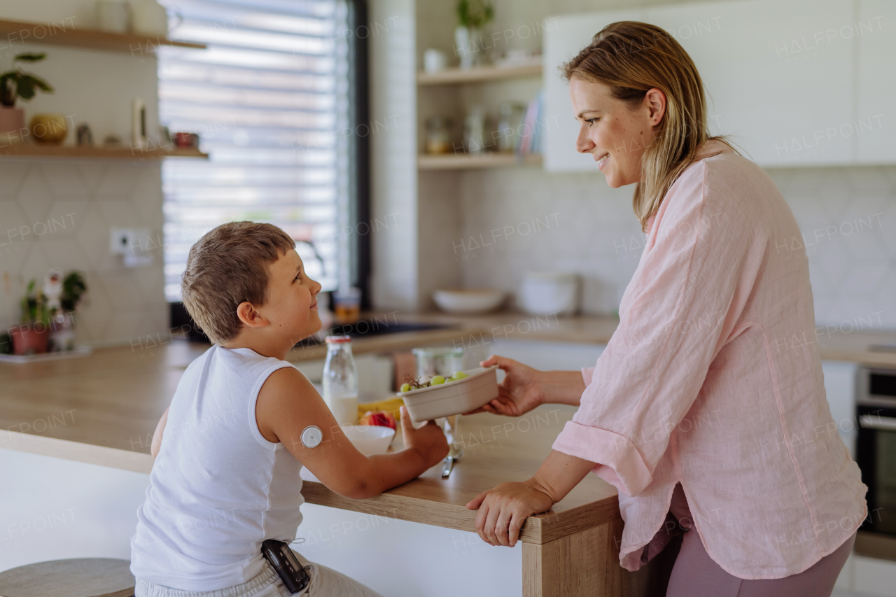 Diabetic boy with a continuous glucose monitor is careful with his diet. Mother checking what her son with diabetes eating. CGM device making life of school boy easier, helping manage his illness and focus on other activities.