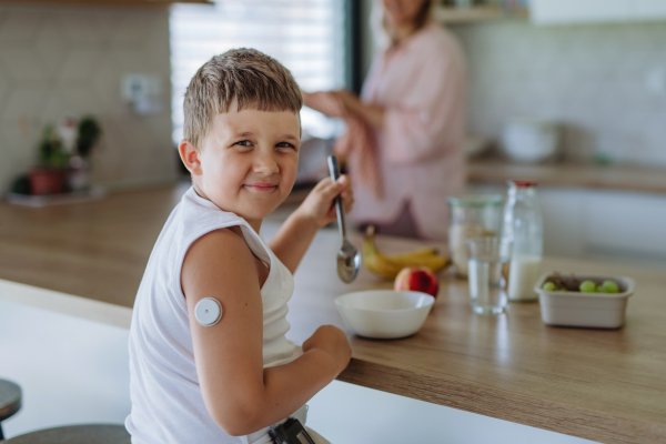 Diabetic boy with a continuous glucose monitor is careful with his diet. Mother checking what her son with diabetes eating. CGM device making life of school boy easier, helping manage his illness and focus on other activities.