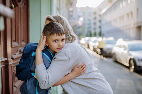 A mother hugs her young son on the way to school, and a mother and boy say goodbye before school.