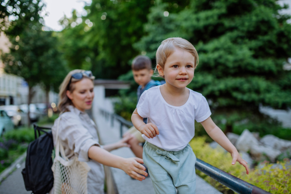 A young mother with zero waste shopping bag with her children and walking in city street street