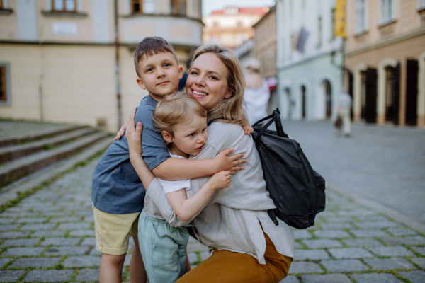 A young mother and little children smiling confident hugging each other standing at street