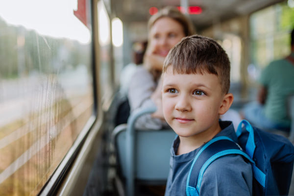 A close-up of little boy travelling to school by bus in the morning, commuting and sustainable lifestyle concept.