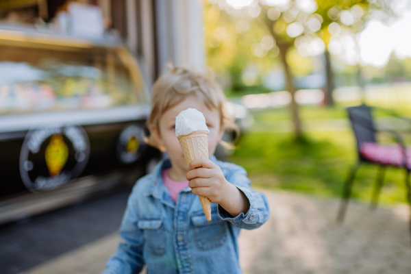 Little girl enjoying ice cream in park during a hot summer day.