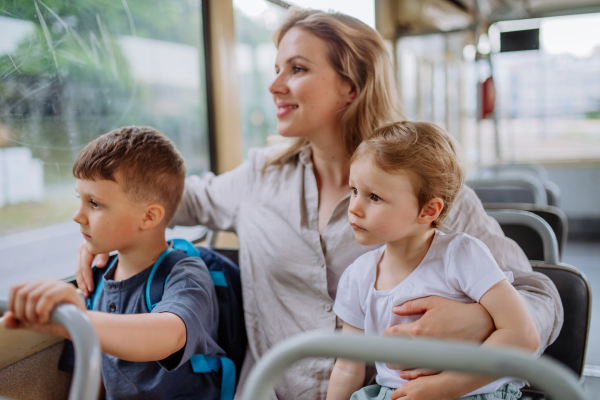 A young mother with little kids travelling in tram in summer, commuting and sustainable lifestyle concept.