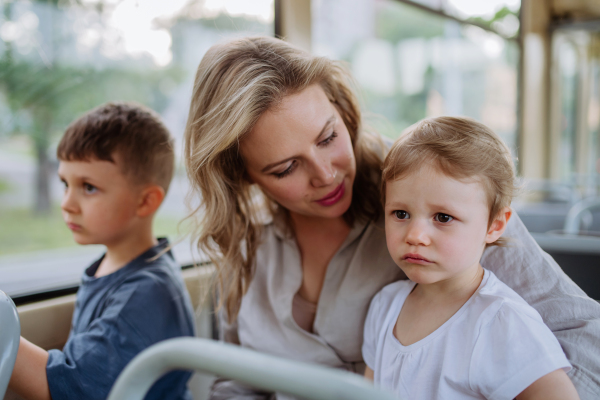 A young mother with little kids travelling in tram in summer, commuting and sustainable lifestyle concept.