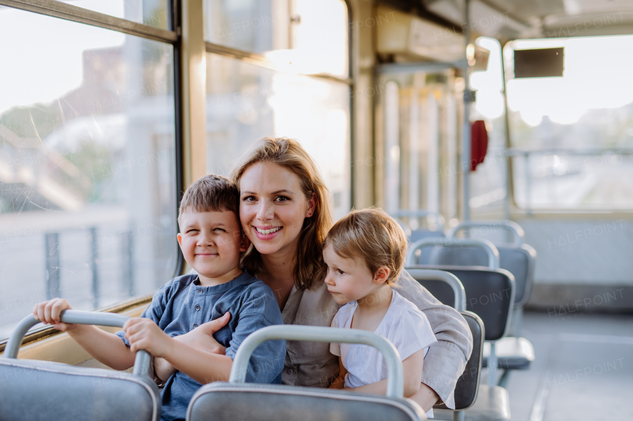 A young mother with little kids travelling in tram in summer, commuting and sustainable lifestyle concept.