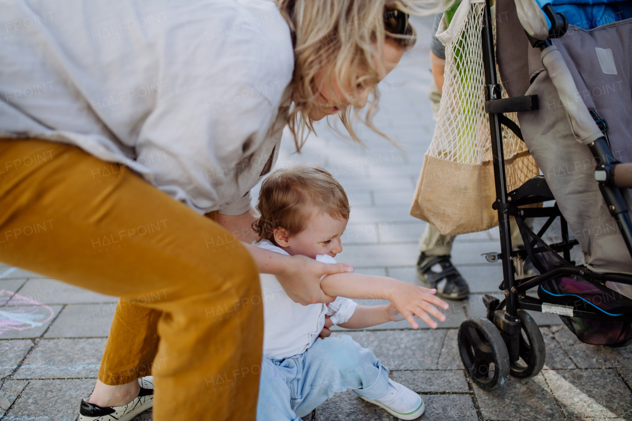 A young mother with zero waste shopping bag with her children and walking in city street, close-up