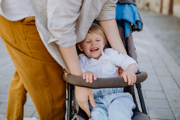 A mother calming a crying child sitting in a stroller while walking down the street