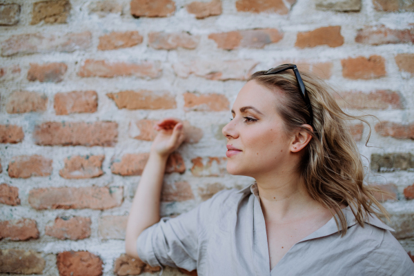 A fashion portrait of young woman with sunglasses in summer on brick wall background