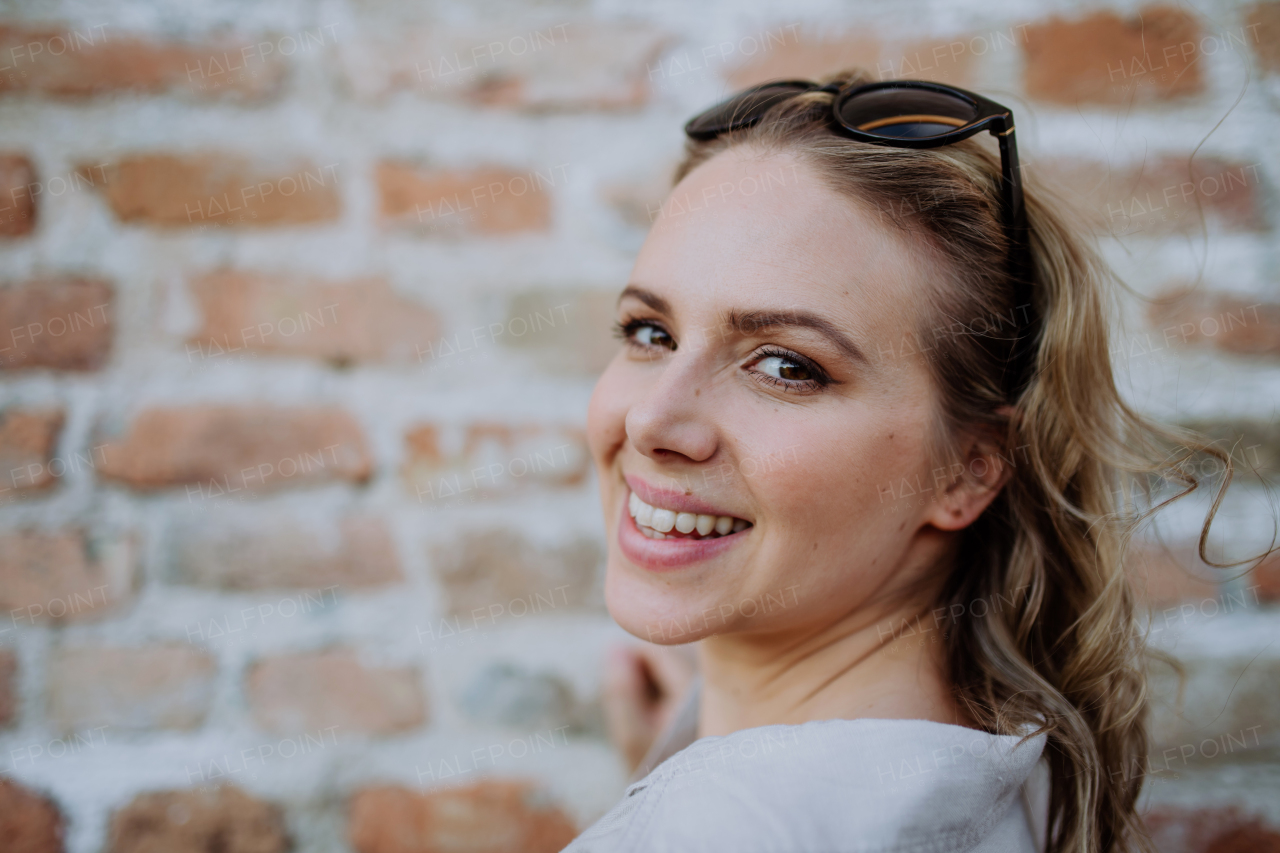 A fashion portrait of young woman with sunglasses in summer on brick wall background