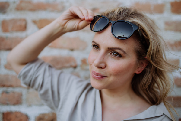 A fashion portrait of young woman with sunglasses in summer on brick wall background