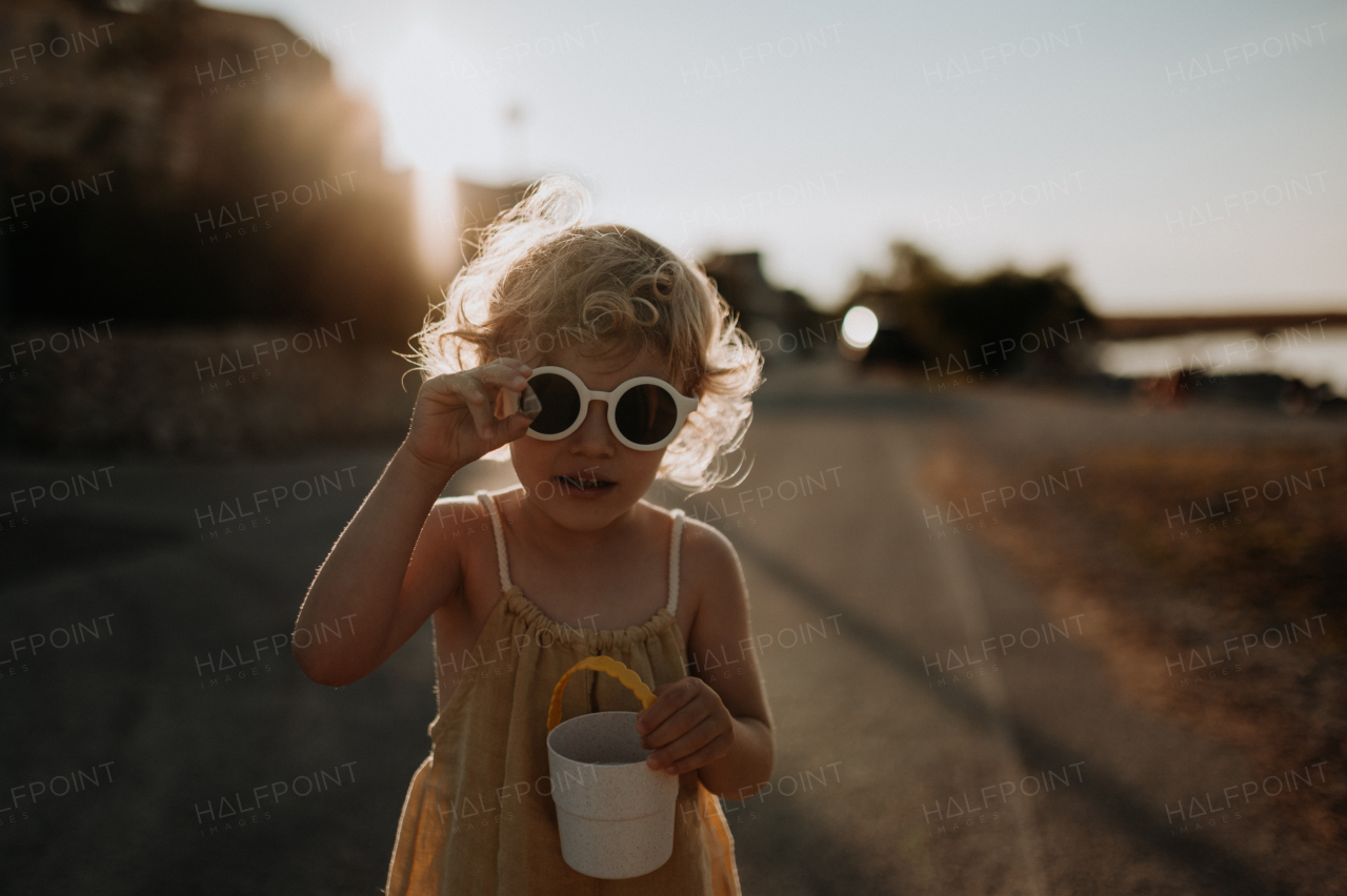 Portrait of blonde girl in summer outfit and sunglasses on walk during summer vacation, concept of beach holiday.