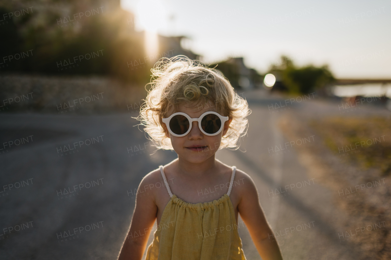 Portrait of blonde girl in summer outfit and sunglasses on walk during summer vacation, concept of beach holiday.