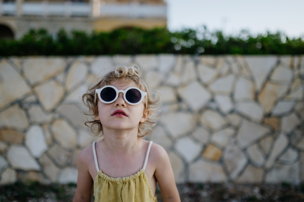 Portrait of blonde girl in summer outfit and sunglasses on walk during summer vacation, concept of beach holiday.