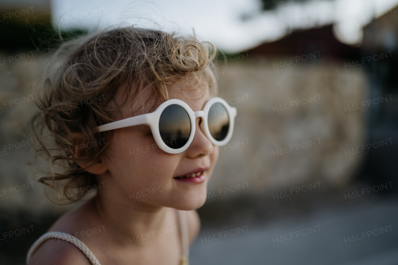 Portrait of blonde girl in summer outfit and sunglasses on walk during summer vacation, concept of beach holiday.