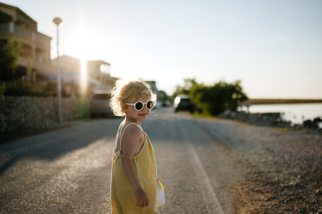 Portrait of blonde girl in summer outfit and sunglasses on walk during summer vacation, concept of beach holiday.