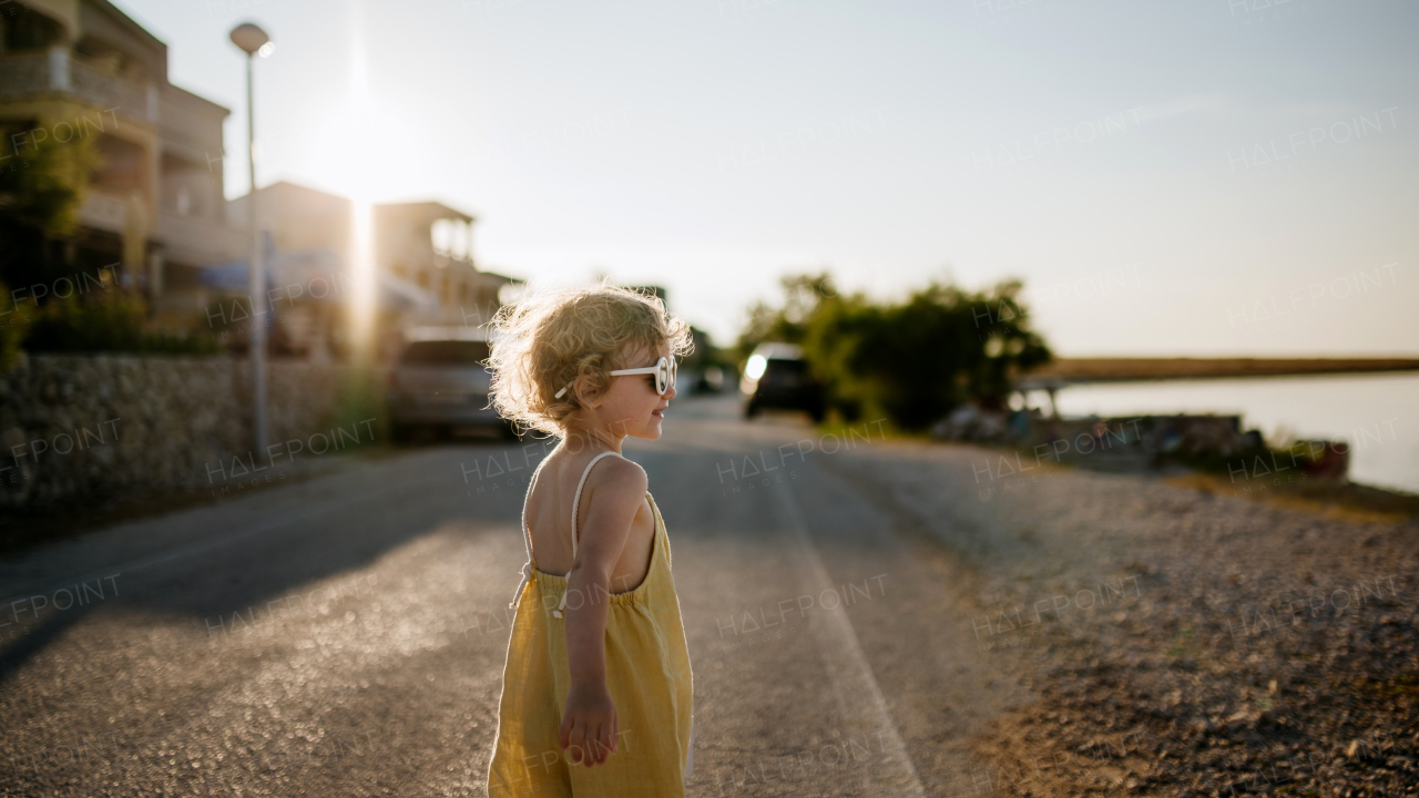 Side view of blonde girl in summer outfit on walk during summer vacation, beach holiday.