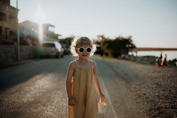 Portrait of blonde girl in summer outfit and sunglasses on walk during summer vacation, concept of beach holiday.