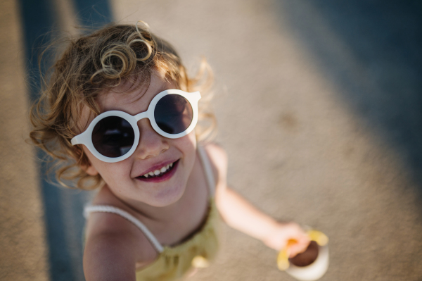 Top view of blonde girl in summer outfit on walk during summer vacation, beach holiday. Portrait from high angle.