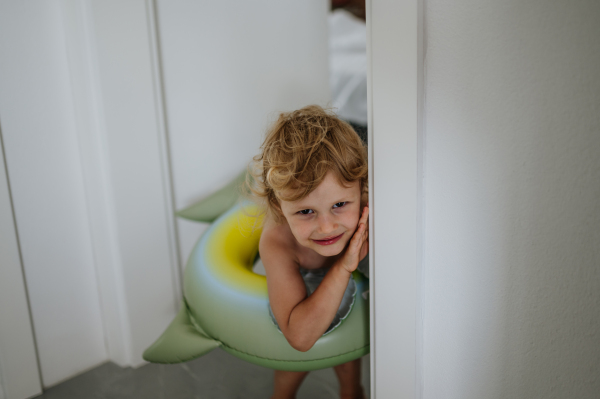 Small girl is excited to go on the beach. Standing in living room in swimsuit and inflatable toy ring.