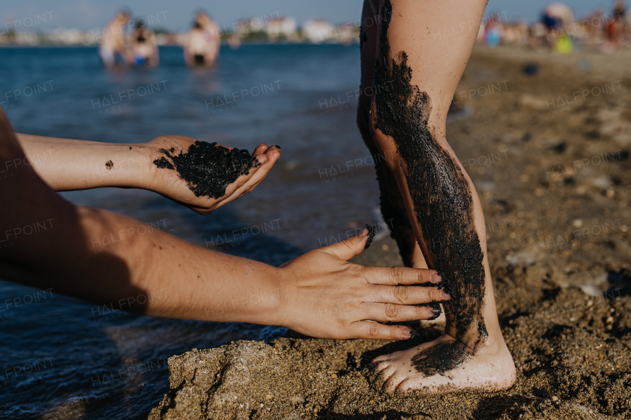 Mother applies healing mud to kids skin. Natural healing mud in Croatia on the beach. Therapeutic mud or peloids rich in minerals and organic substances.