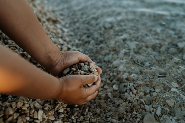 Close up of pebbles in boy's palms with pruney fingers. Seraching for shells in the sand. Concept of summer vacation by sea.