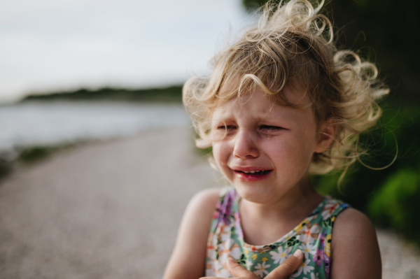 Portrait of crying blonde girl in summer outfit and sunglasses on walk during summer vacation, concept of beach holiday.