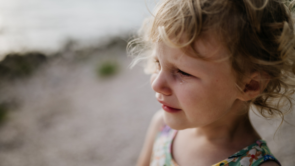 Portrait of crying blonde girl in summer outfit and sunglasses on walk during summer vacation, concept of beach holiday.