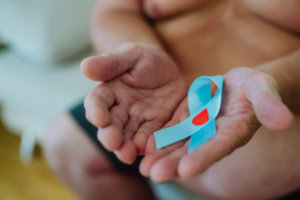 Overweight man holding a blue diabetes support ribbon as a symbol of diabetes awareness. November as Diabetes Awareness Month. 14 November as World Diabetes Day.