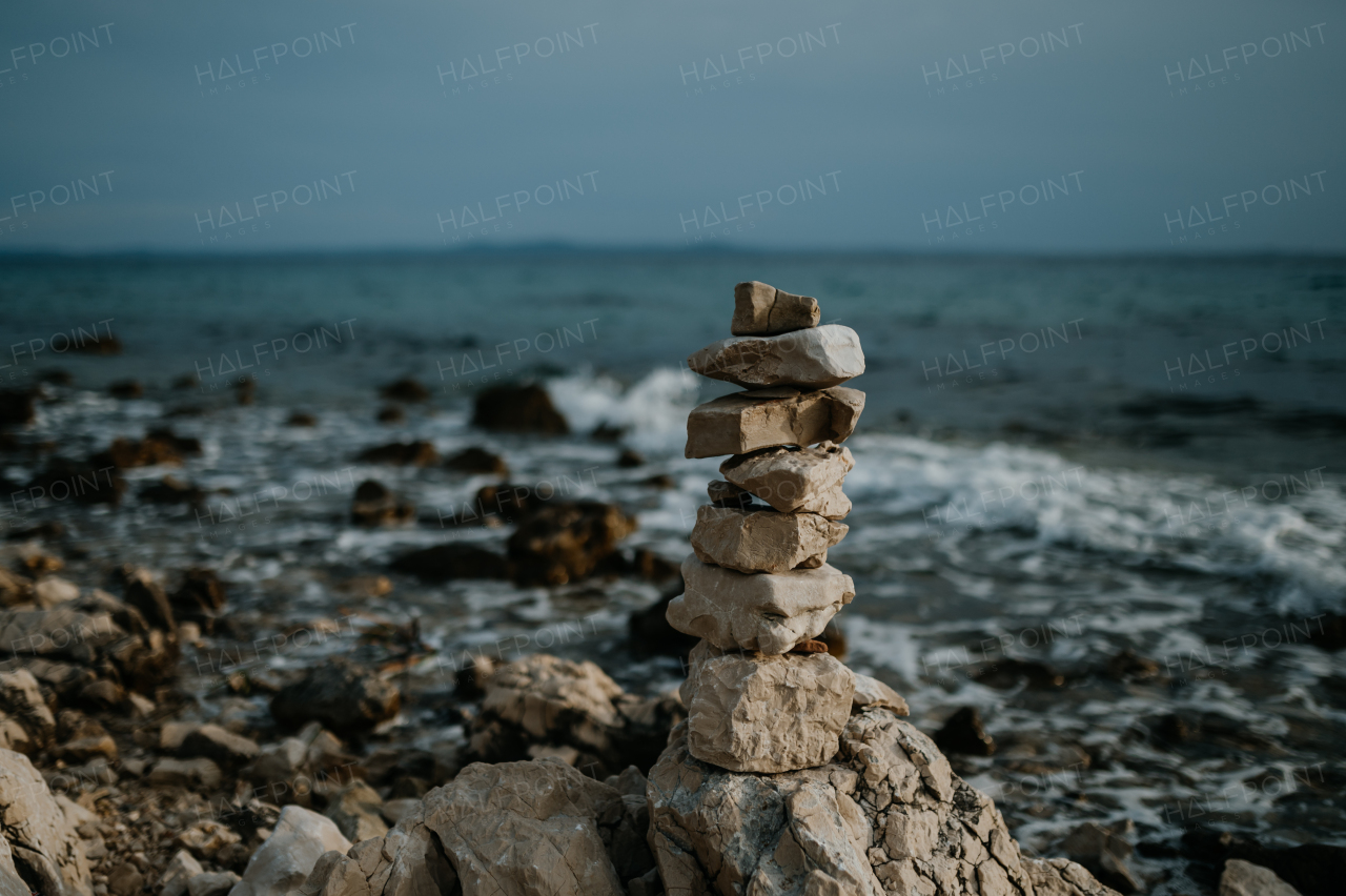 Small cairn from beach stones, with beautiful landscape of Croatia behind, Croatia coast, sea and rocks in water.