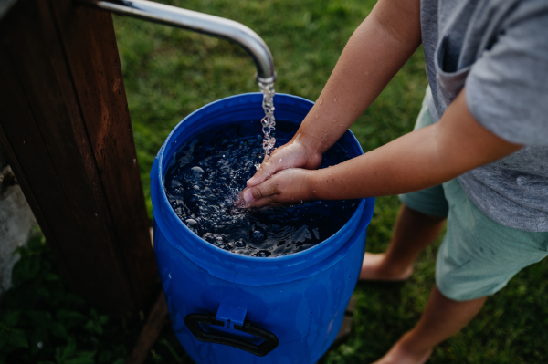 Boy washing his hands with water from a well. Well with a pump for outdoor washing in the garden.