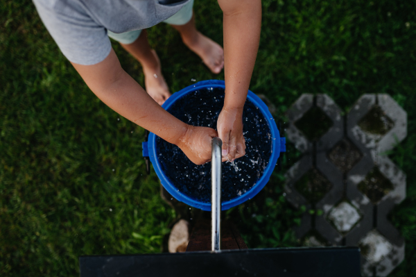 Boy washing his hands with water from a well. Well with a pump for outdoor washing in the garden.