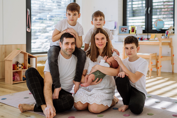 Portrait of big family with four sons enjoying their newborn baby.