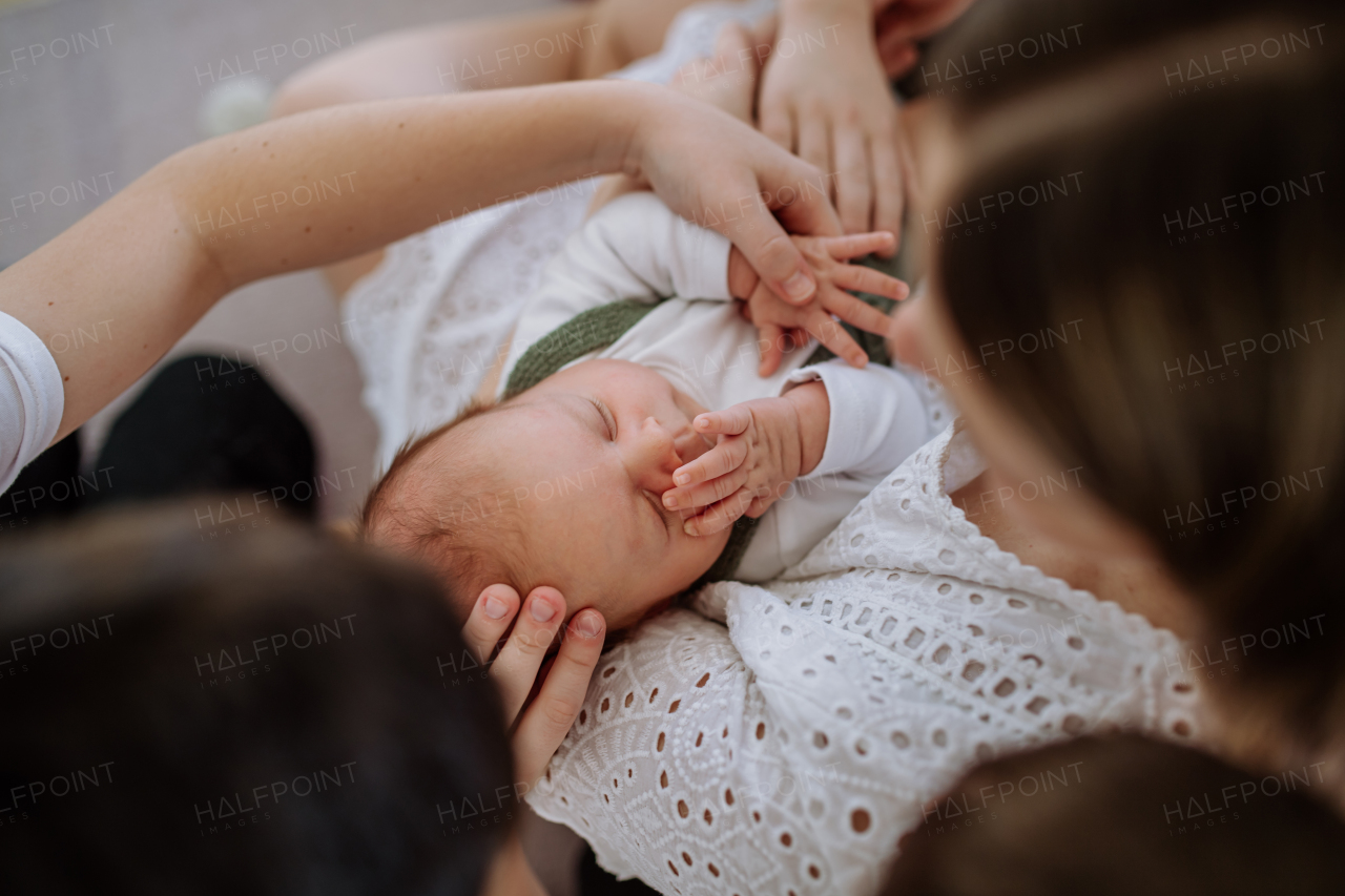 Portrait of woman kissing her newborn baby,other siblings stoking him.