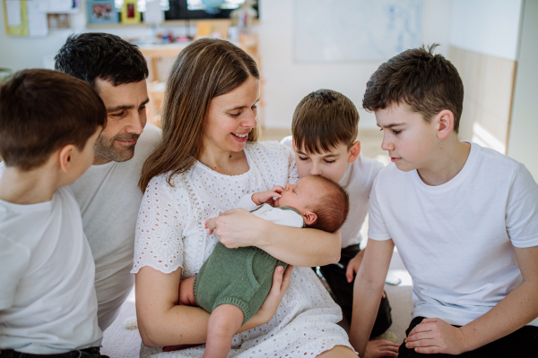 Big family with four sons enjoying their newborn baby.