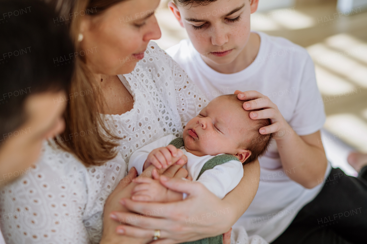 Portrait of mother holding her newborn baby and stroking him with older children.