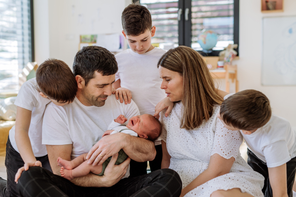 Big family with four sons enjoying their newborn baby.