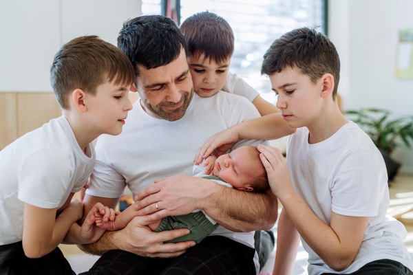 Portrait of a father and his four sons, holding his newborn baby.