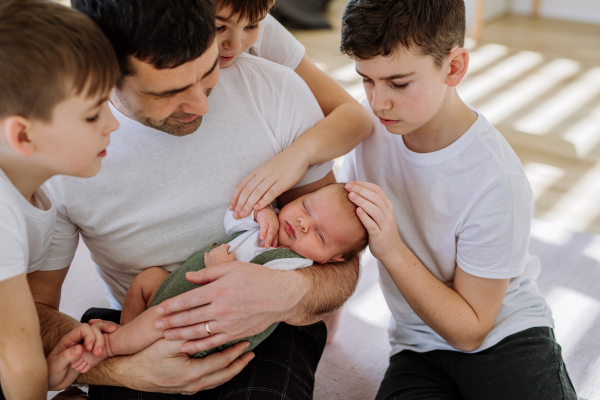 Portrait of a father and his four sons, holding his newborn baby.