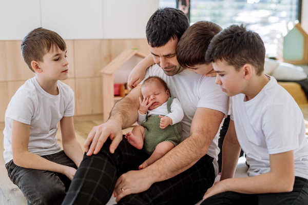 Portrait of a father and his four sons, holding his newborn baby.