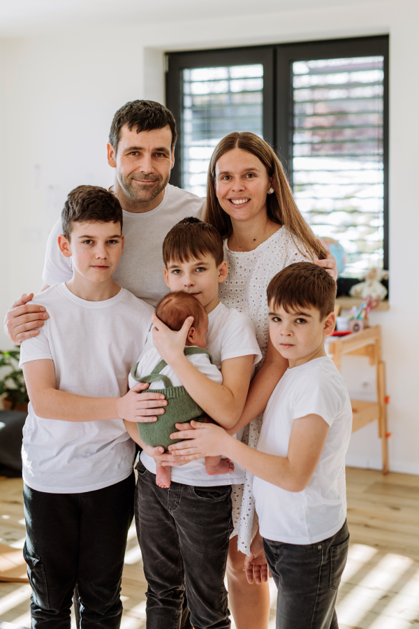 Portrait of big family with four sons enjoying their newborn baby.