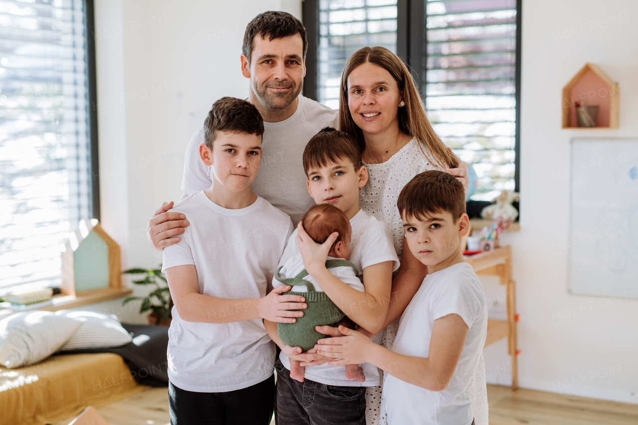 Portrait of big family with four sons enjoying their newborn baby.