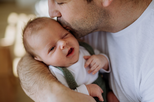 Close-up of father holding and kissing his little new born baby.