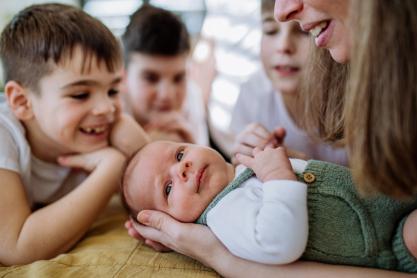 Happy mother and her sons cuddling their newborn baby.